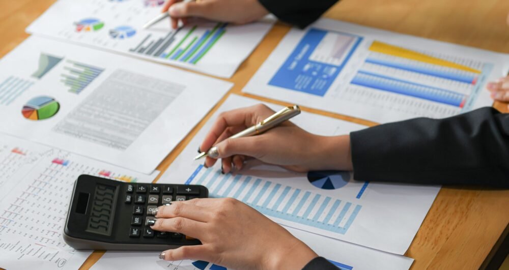 Accountants are analyzing data from the graph of the organization.They use the calculator and point the pen at the graphs.